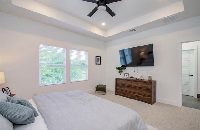 carpeted bedroom featuring a tray ceiling and ceiling fan