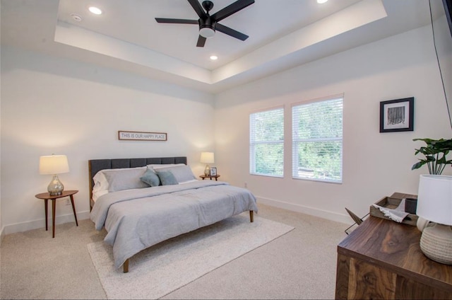 bedroom featuring ceiling fan, light colored carpet, and a raised ceiling