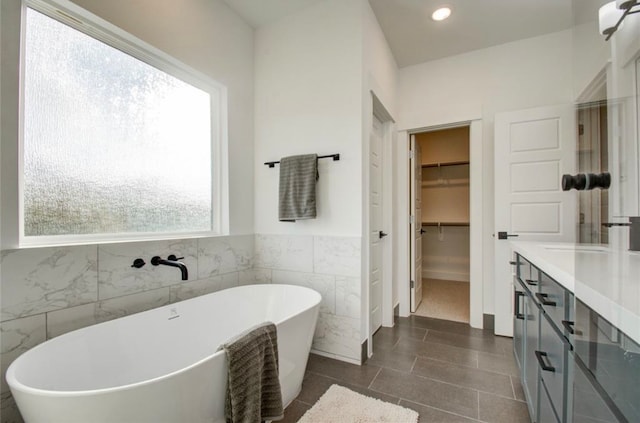 bathroom featuring a bathtub, tile walls, vanity, and tile patterned floors