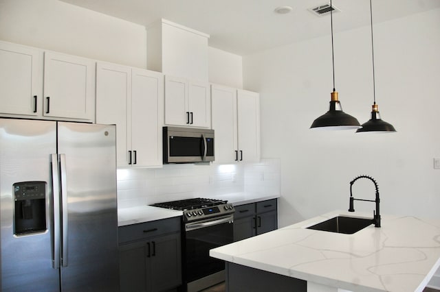 kitchen with white cabinets, appliances with stainless steel finishes, pendant lighting, and sink