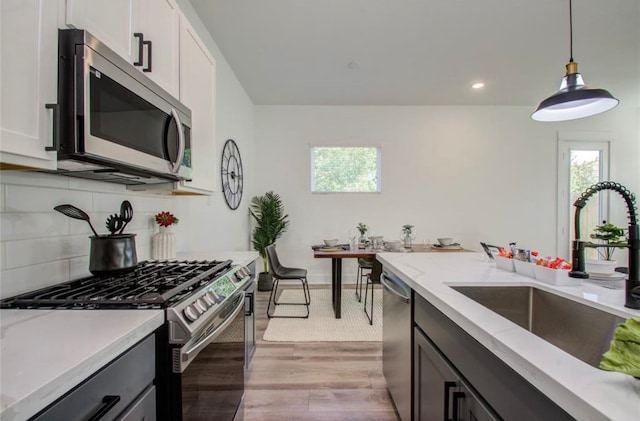 kitchen with decorative light fixtures, light hardwood / wood-style flooring, stainless steel appliances, and white cabinets