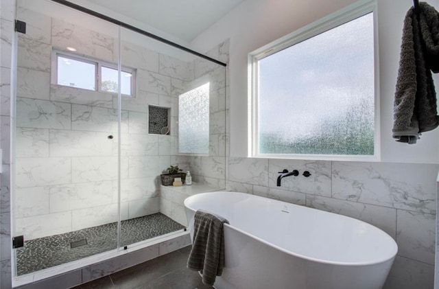 bathroom with shower with separate bathtub, tile patterned floors, and tile walls