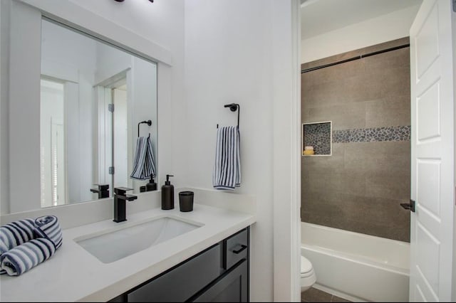 full bathroom featuring tiled shower / bath combo, vanity, and toilet