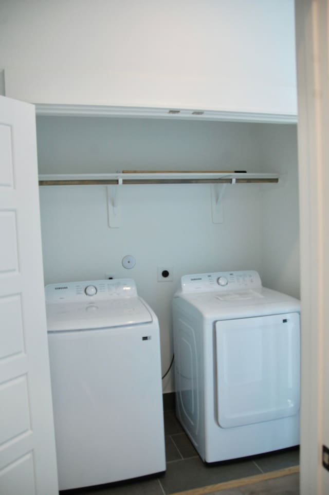 clothes washing area featuring washing machine and clothes dryer and dark tile patterned flooring