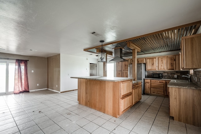 kitchen with hanging light fixtures, tasteful backsplash, a kitchen island, range hood, and sink