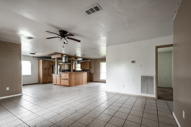 unfurnished living room featuring ceiling fan, light tile patterned floors, and a textured ceiling