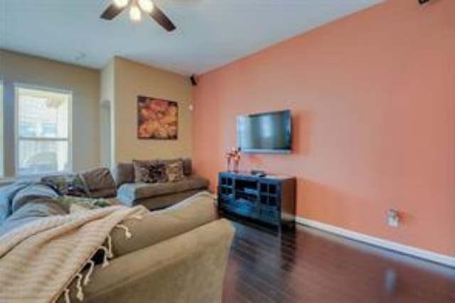 living room featuring ceiling fan and dark wood-type flooring