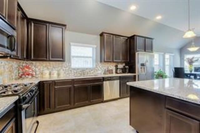 kitchen featuring lofted ceiling, hanging light fixtures, decorative backsplash, stainless steel appliances, and dark brown cabinetry