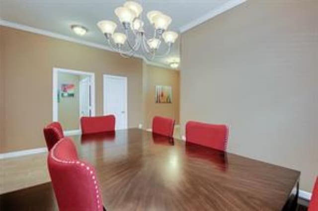 dining space featuring dark hardwood / wood-style flooring, a chandelier, and crown molding