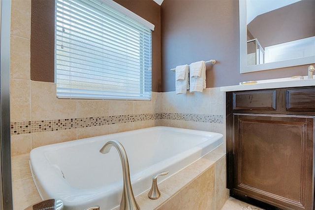 bathroom with tile walls, a wealth of natural light, tiled tub, and vanity