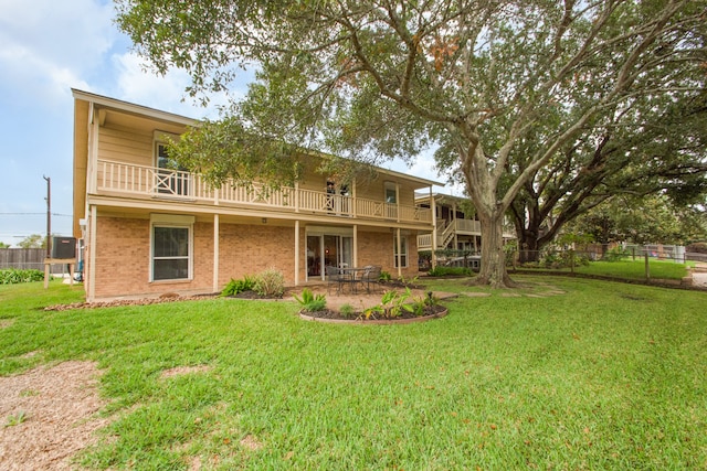 rear view of house with central AC unit, a balcony, and a lawn