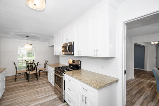 kitchen featuring light hardwood / wood-style flooring, decorative backsplash, white cabinetry, and appliances with stainless steel finishes