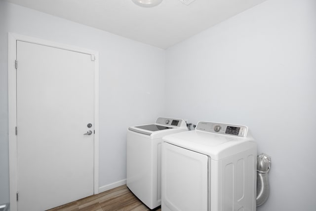 clothes washing area with light hardwood / wood-style flooring and washer and dryer