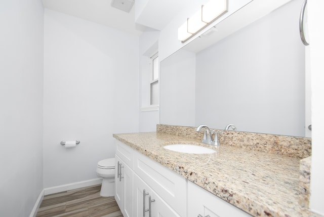 bathroom with wood-type flooring, vanity, and toilet