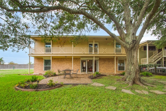 back of house featuring a balcony, a patio area, and a lawn