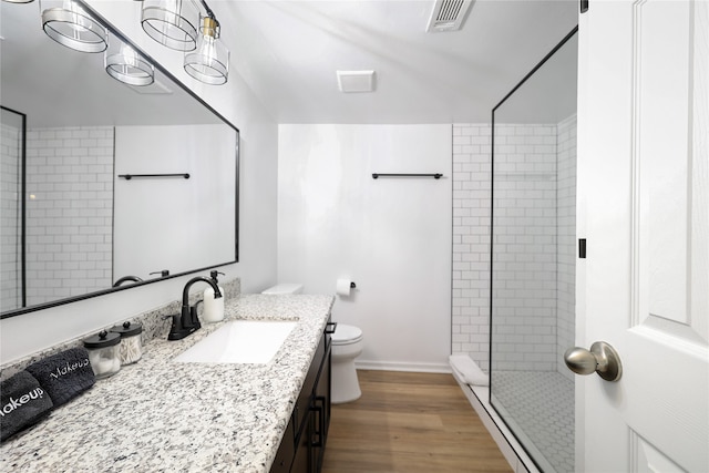 bathroom featuring wood-type flooring, a shower with shower door, vanity, and toilet