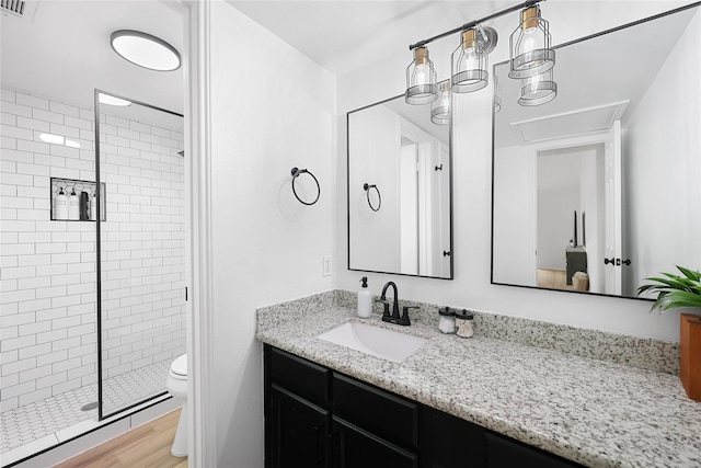 bathroom featuring wood-type flooring, a shower with door, vanity, and toilet