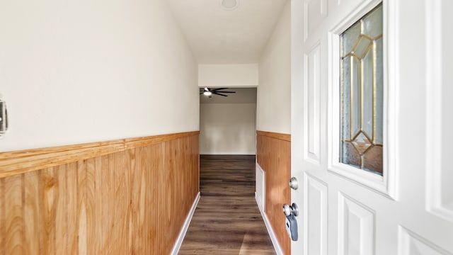 hallway with a textured ceiling, wooden walls, and dark hardwood / wood-style floors