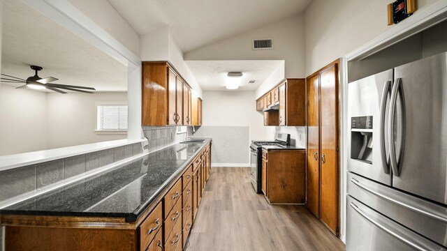 kitchen with light hardwood / wood-style floors, lofted ceiling, decorative backsplash, stainless steel appliances, and ceiling fan