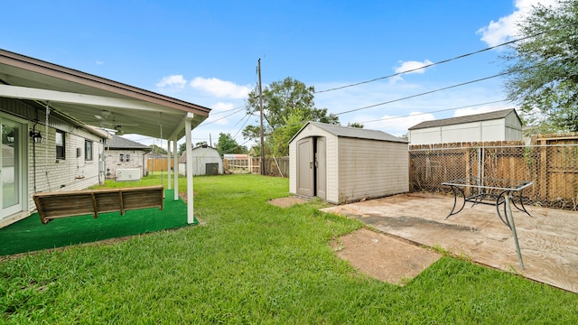 view of yard with ceiling fan, a storage shed, and a patio area