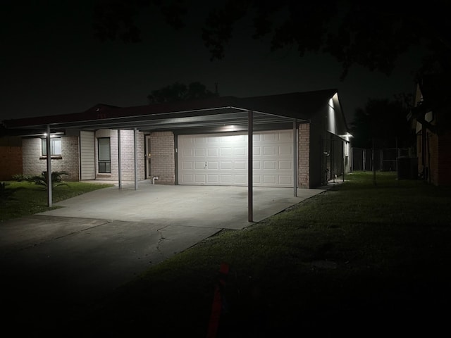 garage at night featuring a lawn and a carport