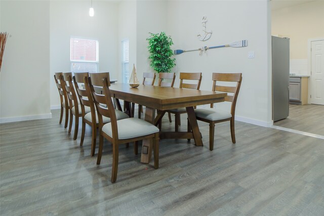 dining space with light hardwood / wood-style flooring and a high ceiling