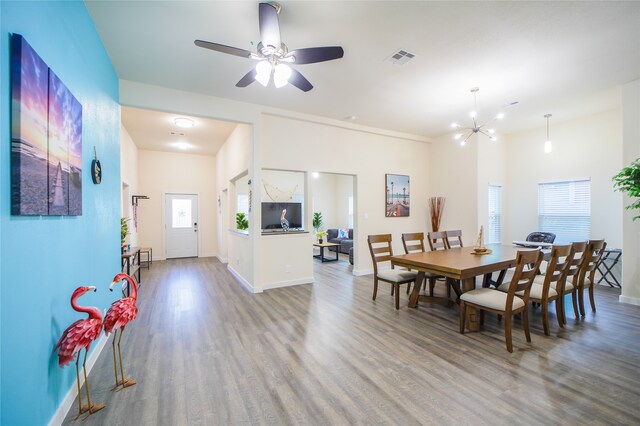 dining area featuring ceiling fan with notable chandelier and wood-type flooring