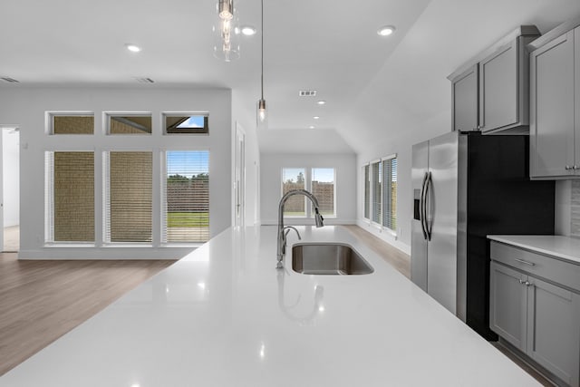 kitchen with gray cabinets, sink, light wood-type flooring, and lofted ceiling