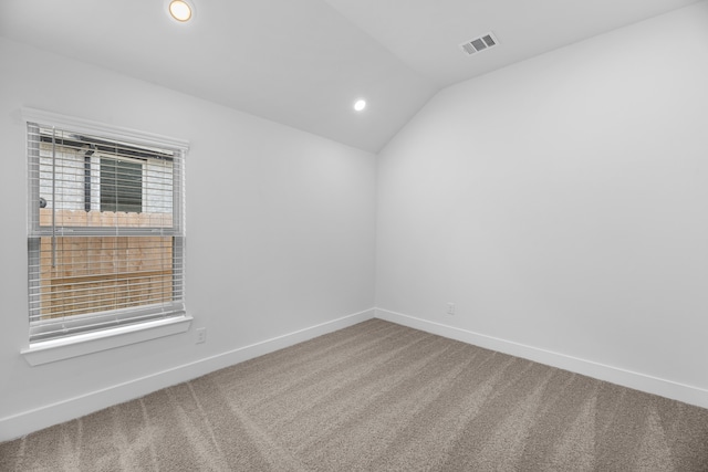 carpeted spare room featuring vaulted ceiling and plenty of natural light