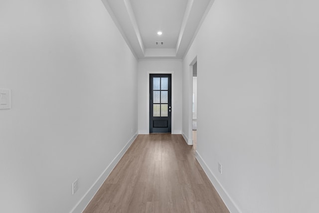 doorway to outside with light hardwood / wood-style flooring and a tray ceiling