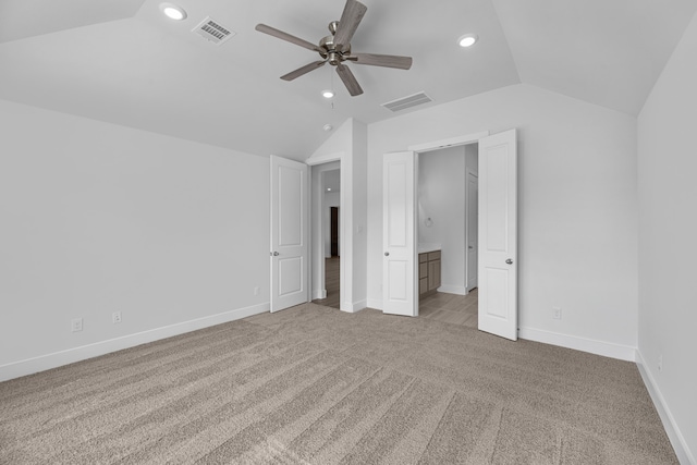 unfurnished bedroom featuring light colored carpet, lofted ceiling, ceiling fan, and connected bathroom