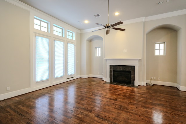 unfurnished living room with ceiling fan, a tile fireplace, crown molding, and dark hardwood / wood-style flooring