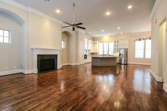 unfurnished living room featuring a tile fireplace, ornamental molding, dark hardwood / wood-style flooring, and ceiling fan