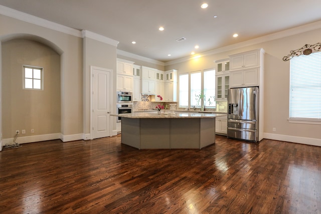 kitchen featuring light stone counters, tasteful backsplash, a kitchen island, stainless steel appliances, and dark hardwood / wood-style flooring