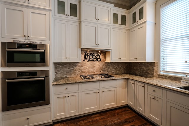 kitchen with white cabinetry, dark wood-type flooring, light stone counters, tasteful backsplash, and stainless steel appliances