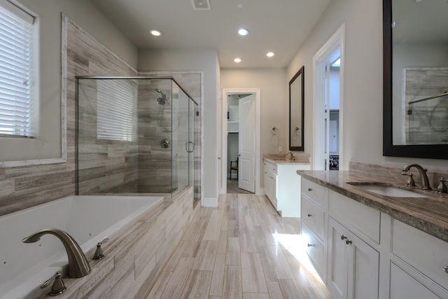 bathroom with plus walk in shower, wood-type flooring, and vanity