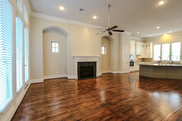 unfurnished living room featuring ceiling fan, a fireplace, ornamental molding, and dark hardwood / wood-style flooring