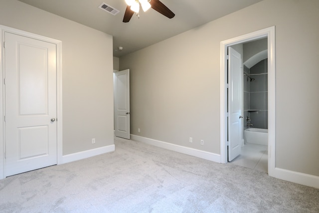 unfurnished bedroom featuring light colored carpet, ceiling fan, and ensuite bathroom