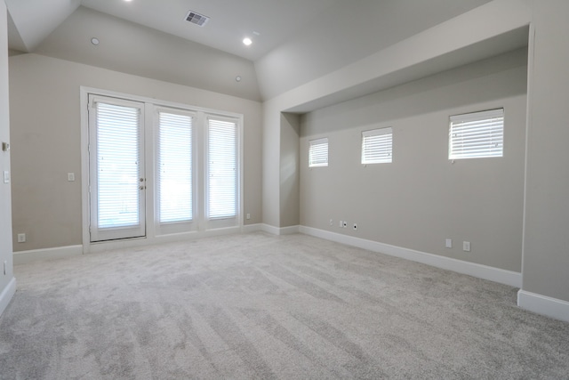 carpeted empty room with lofted ceiling and plenty of natural light