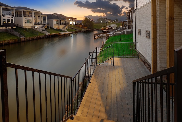 deck at dusk featuring a water view