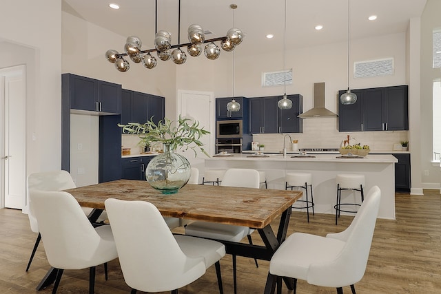 dining area with a towering ceiling, sink, and light hardwood / wood-style flooring