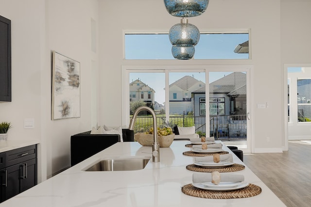 dining area featuring light hardwood / wood-style floors, a towering ceiling, and sink