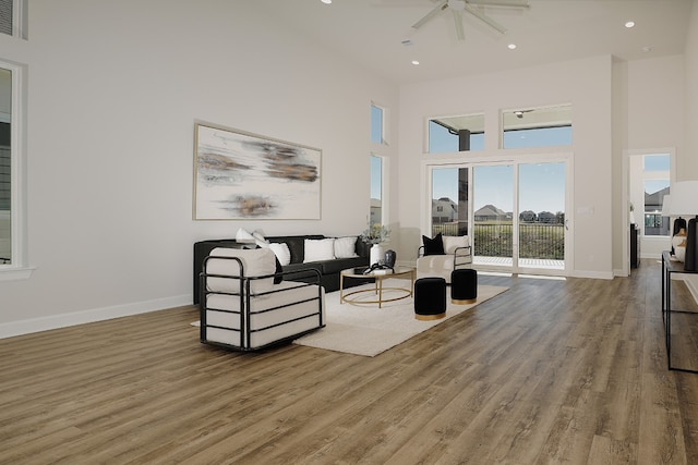 living room featuring ceiling fan, wood-type flooring, and a towering ceiling