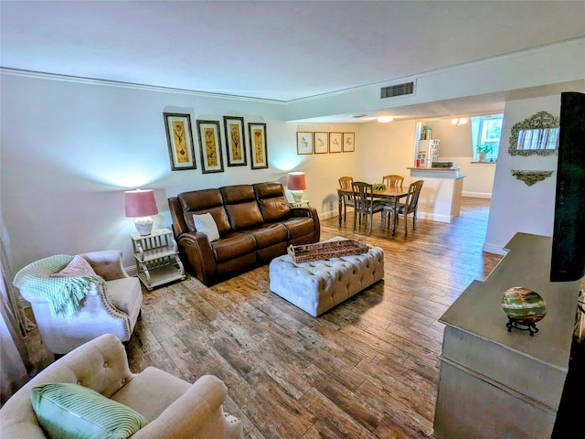 living room featuring wood-type flooring and crown molding