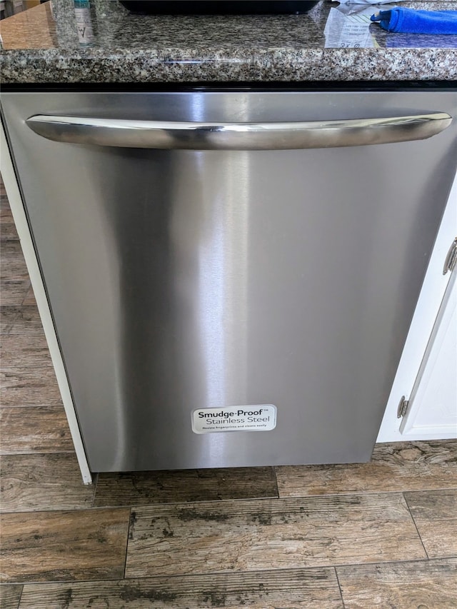 details with wood-type flooring, stainless steel dishwasher, dark stone countertops, and white cabinets