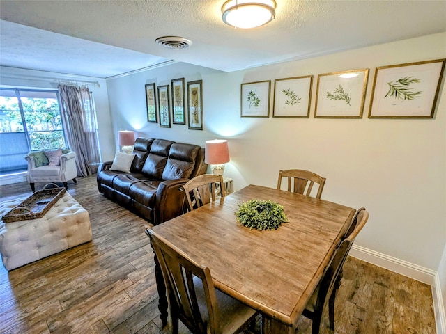 dining area with ornamental molding, a textured ceiling, and hardwood / wood-style floors