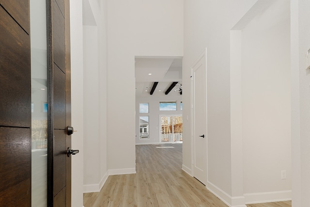 hallway featuring beamed ceiling and light wood-type flooring