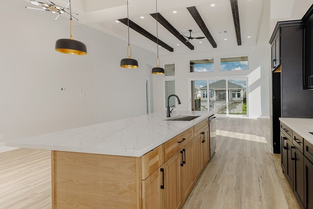 kitchen featuring a center island with sink, light wood-type flooring, decorative light fixtures, light brown cabinets, and sink