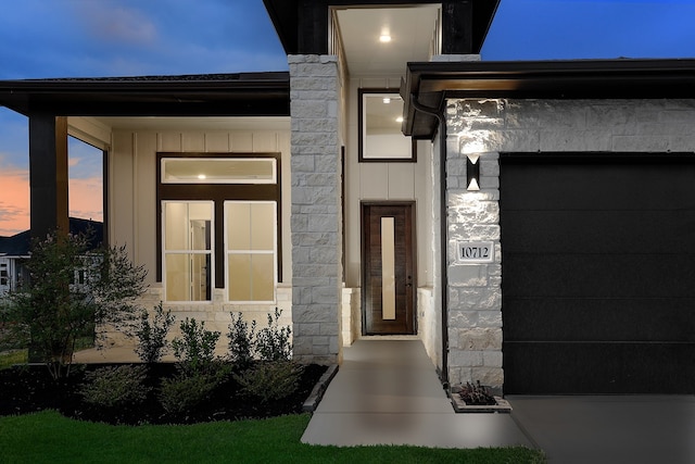 exterior entry at dusk featuring a garage