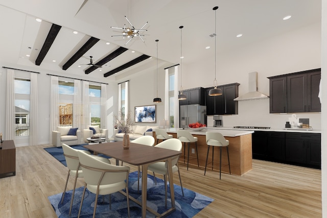 dining space with beamed ceiling, a notable chandelier, light hardwood / wood-style floors, and a towering ceiling